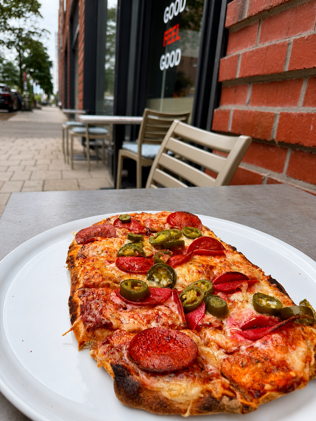 Frisch gebackene Pizza mit Salami und Jalapeños auf dem Außentisch vor Hafen Happen in der HafenCity
